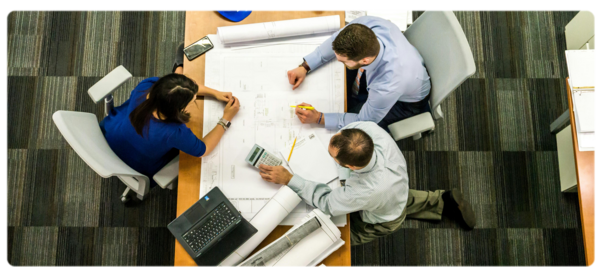 Three people sit around a conference table going over documents